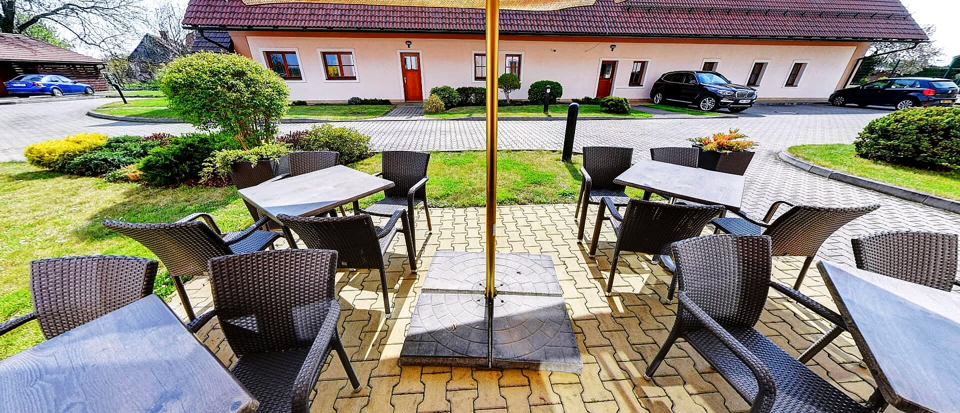 Zahradní terasa se stolky pod slunečníkem u penzionu v Hradci Králové